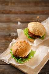 Image showing Homemade hamburgers and french fries on wooden table