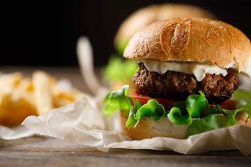 Image showing Homemade tasty burger and french fries on wooden table