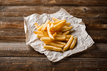 Image showing French fries on wooden table.