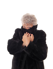 Image showing Senior woman hiding in her fur coat.