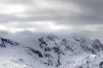 Image showing Snowy mountains in haze and storm clouds