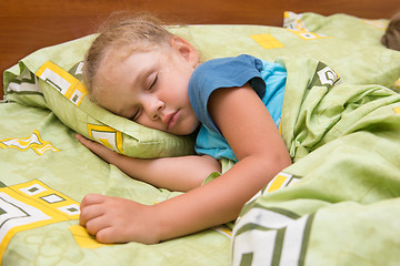 Image showing Little girl sleeping on her side in bed with his hand under the pillow and covered with a blanket