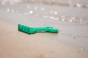 Image showing Childrens toy rake, forgotten on the shore near the water