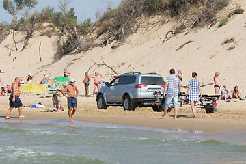 Image showing Anapa, Russia - September 20, 2015: Jeep with insolent driver rides on the beach with holidaymakers