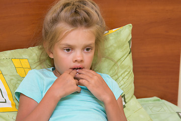 Image showing Six-year girl looks thoughtfully at one point and keeps finger in mouth