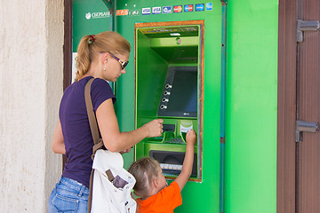 Image showing Anapa, Russia - September 20, 2015: A young girl with the child to withdraw money from the ATM Sberbank