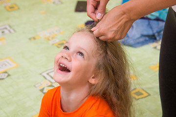 Image showing A girl of four years old sitting and laughing happily, when she made her hair