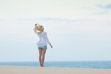 Image showing Woman on sandy beach in white shirt in morning. 