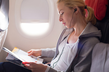 Image showing Woman reading magazine on airplane.