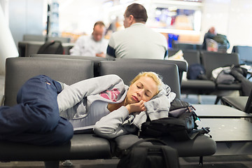 Image showing Tired female traveler sleeping on airport.