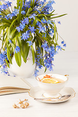 Image showing Tea with  lemon and bouquet of  blue primroses on the table