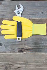 Image showing yellow safety glove and a pipe wrench