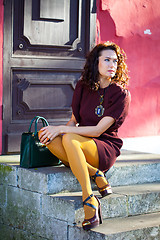 Image showing woman in a burgundy dress sitting on the old porch