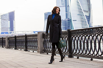 Image showing middle-aged woman in a fashionable dark coat and a green handbag