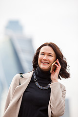 Image showing business woman in a bright coat talking on a cell phone