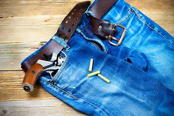 Image showing old blue jeans with silver revolver in his pocket