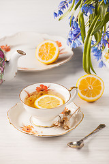 Image showing Tea with  lemon and bouquet of  blue primroses on the table