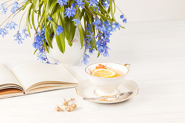 Image showing Tea with  lemon and bouquet of  blue primroses on the table