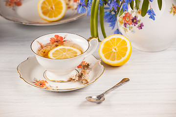 Image showing Tea with  lemon and bouquet of  blue primroses on the table