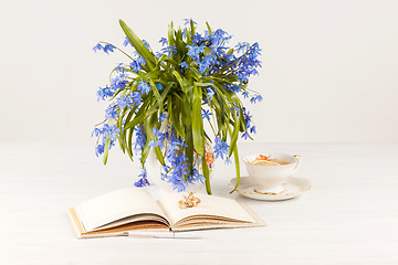 Image showing Tea with  lemon and bouquet of  blue primroses on the table