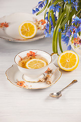 Image showing Tea with  lemon and bouquet of  blue primroses on the table