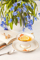 Image showing Tea with  lemon and bouquet of  blue primroses on the table