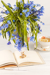 Image showing Tea with  lemon and bouquet of  blue primroses on the table