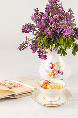 Image showing Tea with  lemon and bouquet of  lilac primroses on the table