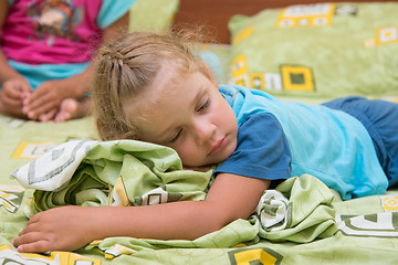 Image showing The little girl sleeps on a double bed crumpling under the blanket