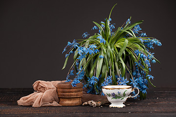 Image showing Tea with  lemon and bouquet of  blue primroses on the table