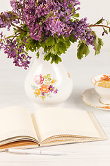 Image showing Tea with  lemon and bouquet of  lilac primroses on the table