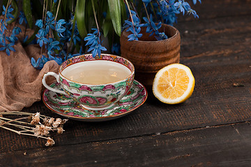 Image showing Tea with  lemon and bouquet of  blue primroses on the table