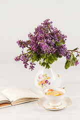 Image showing Tea with  lemon and bouquet of  lilac primroses on the table