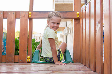Image showing Four-year girl sitting on a wooden platform personal game complex