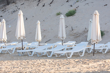 Image showing Rows of empty chairs on the beach with a deflated parasols