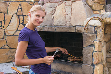 Image showing Young slim woman prepares the meat in barbecue grill