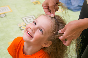 Image showing  four years old girl laughs as she braided long hair