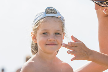 Image showing Mom rubs sunscreen face pretty child