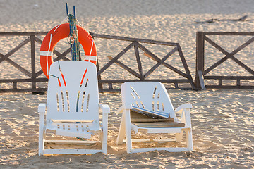 Image showing Two old beach chairs stand near the lifeline on the sandy beach