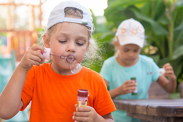 Image showing Little girls enthusiastically inflated bubbles in the street