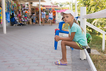 Image showing Tired girl sits about six years of trade pavilions with summer goods