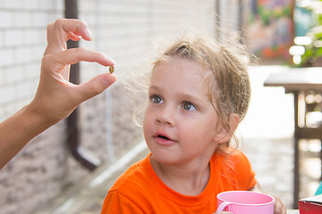 Image showing Four-year girl showing a pea, which she treats with great interest