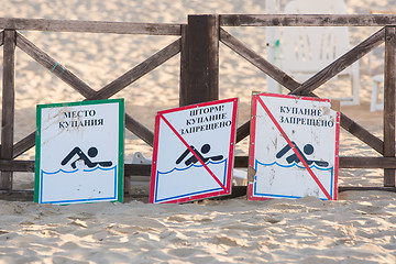 Image showing Anapa, Russia - September 21, 2015: Signs - bathing place, storm, swimming prohibited and swimming forbidden - lie on the sandy beach near the fence with a parasol