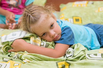 Image showing Little girl sitting on a double bed and frightened looks into the distance