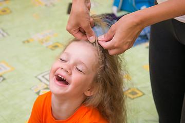 Image showing A girl of four years old sitting happily when she do her hair