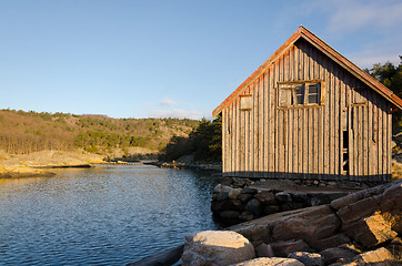 Image showing Old boathouse standing betwen the water 