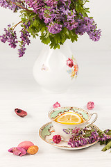 Image showing Tea with  lemon and bouquet of  lilac primroses on the table