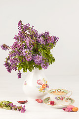 Image showing Tea with  lemon and bouquet of  lilac primroses on the table