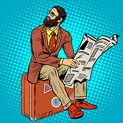 Image showing Bearded hipster traveler reading a newspaper