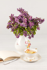 Image showing Tea with  lemon and bouquet of  lilac primroses on the table